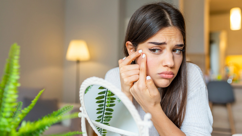 woman popping pimple in mirror