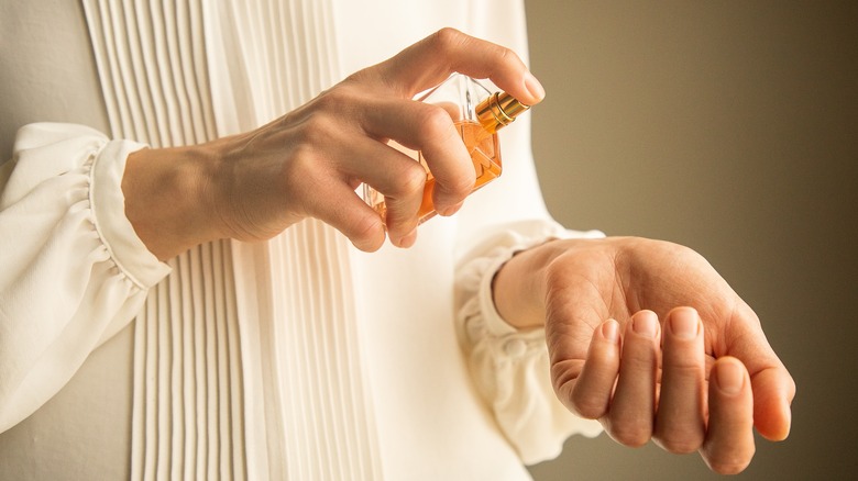 woman spraying perfume on wrist