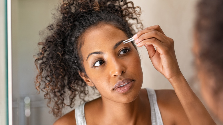 woman tweezing her brows