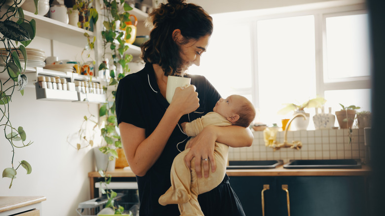 A mother holding her baby in the kitchen