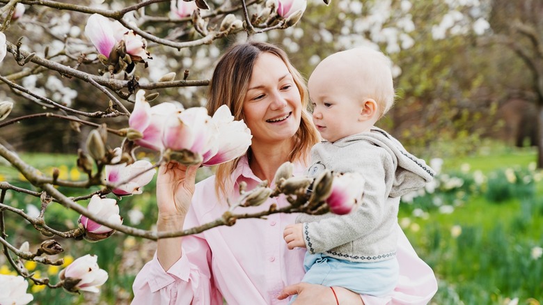 A woman and her baby looking at flowers.