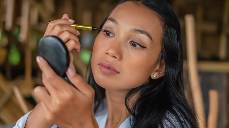 Woman putting on eyeliner