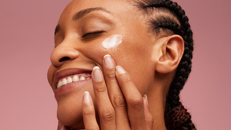 Woman applying lotion on face