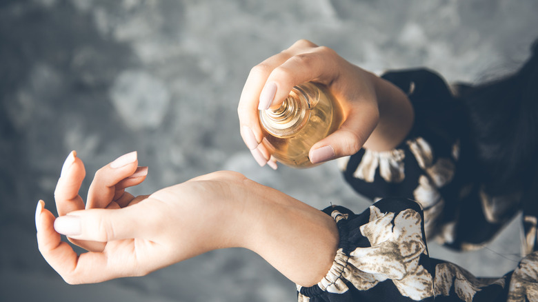 person spraying perfume on wrist