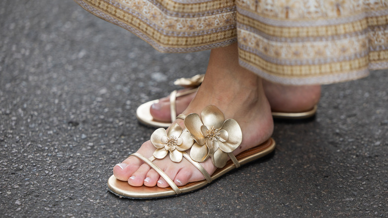 A guest gold sandals with large floral embellishments