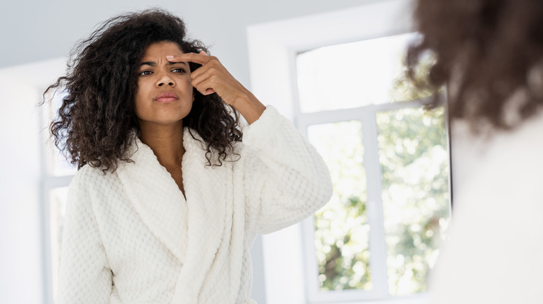 Woman looking at skin in mirror