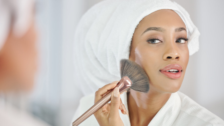 Woman applies setting powder with brush