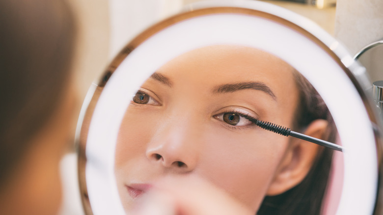 Woman applying mascara in mirror