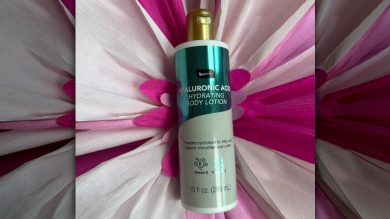 A bottle of B.Pure's Hyaluronic Acid Hydrating Body Lotion on a floral backdrop