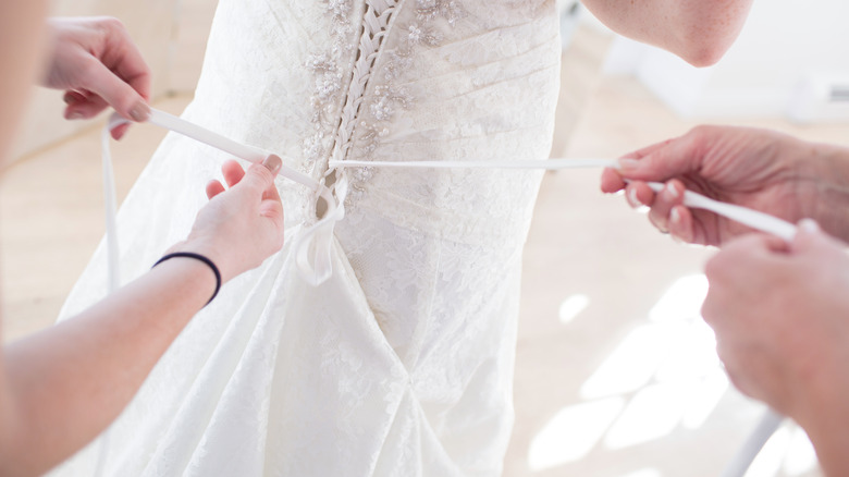 Wedding dress bustle being fastened