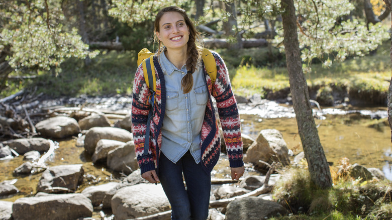 Woman smiling as she is hiking through woods