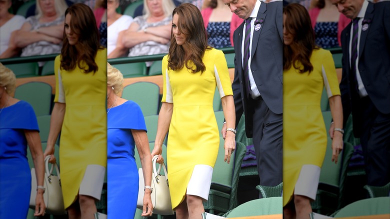 Kate Middleton wearing a yellow dress with white accents and carrying a white purse at Wimbledon in 2016.