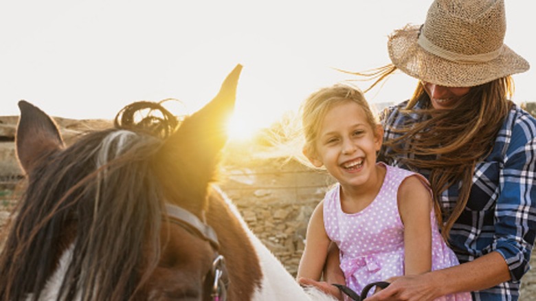 A woman and her young daughter riding a horse.
