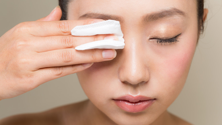 Woman removing makeup from eyes using cotton pad
