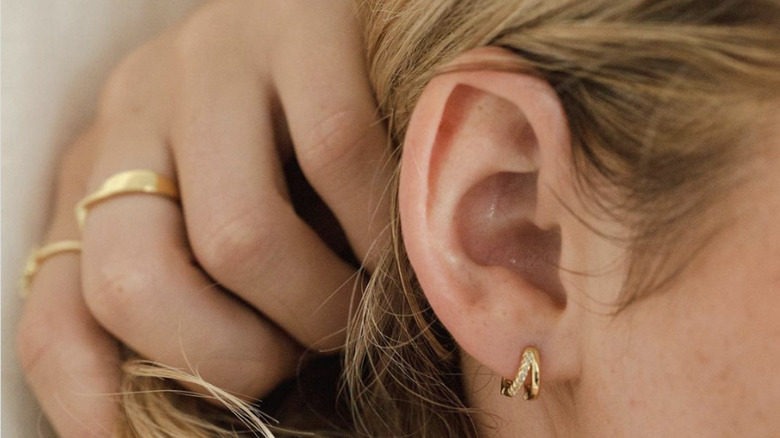 Gold huggie earrings on ear