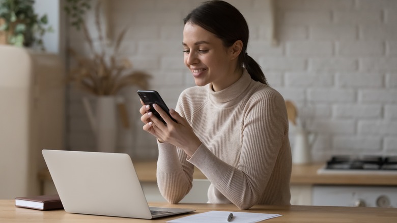 Woman smiles at cell phone