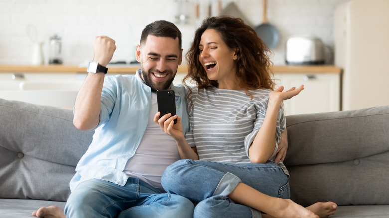 Excited couple sitting on couch