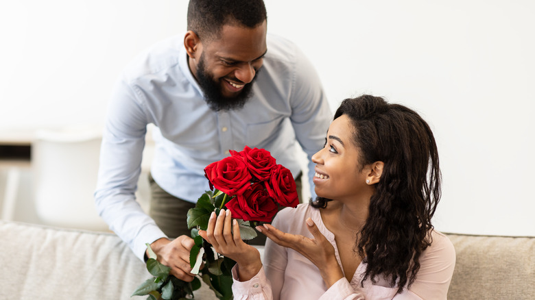 Man giving sitting woman roses