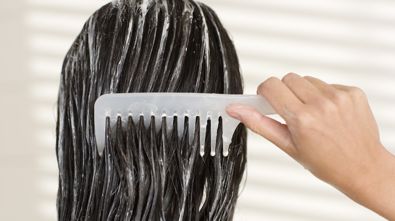 woman combing conditioner through hair