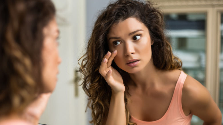 woman examining face in mirror