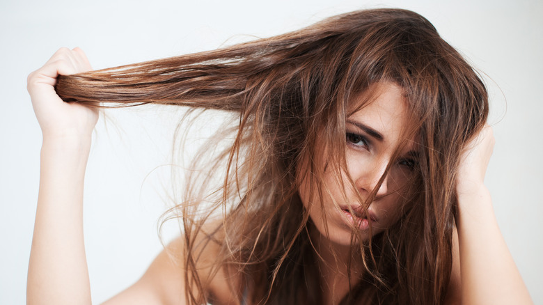 Woman pulling her dirty, oily hair