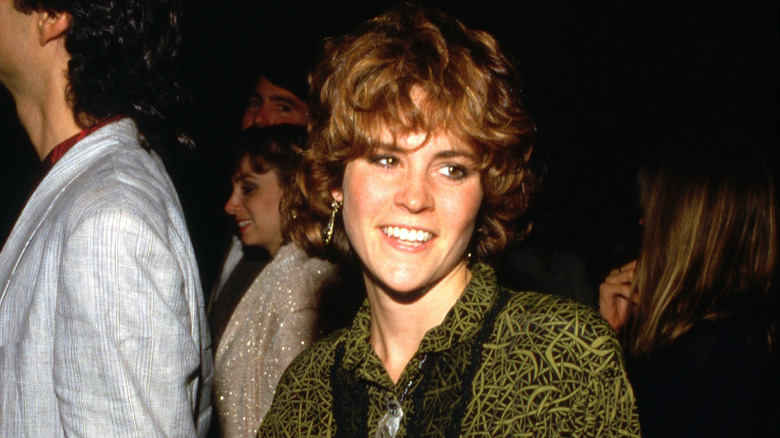 Ally Sheedy smiling in a green-and-black outfit