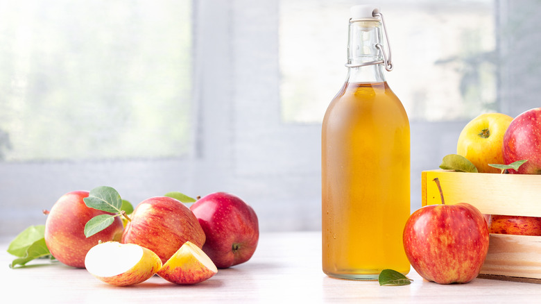 Apple cider vinegar surrounded by apples