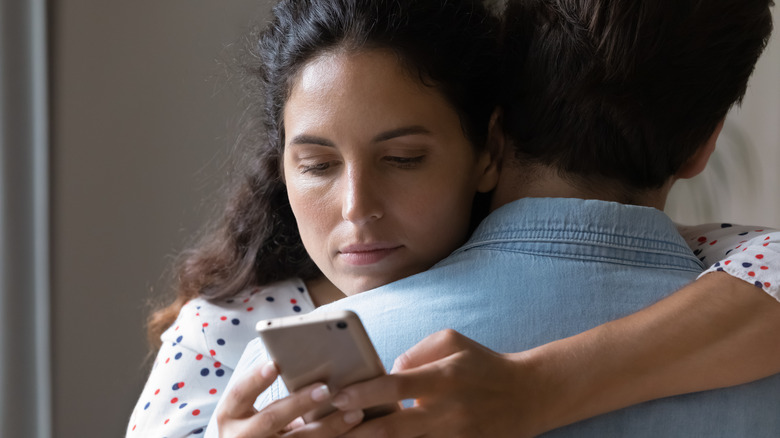 woman texting behind man