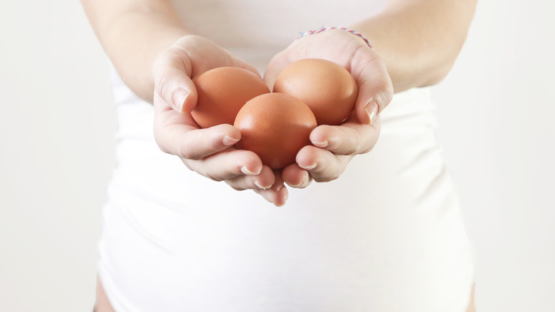 pregnant woman holding eggs