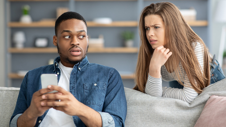 Angry girl looking at boyfriend's phone