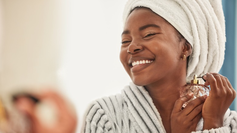 Woman spraying perfume on neck