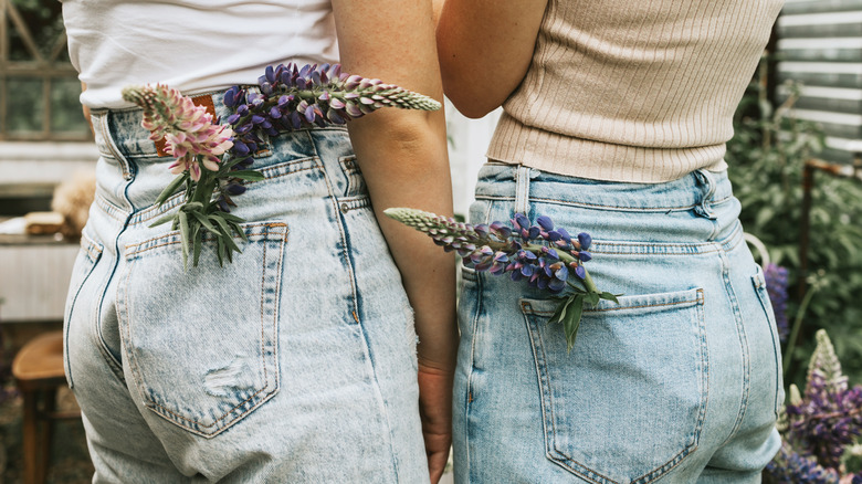 Models posing with flowers in pockets of denim jeans