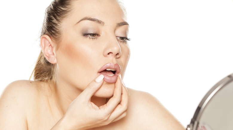 A woman inspecting her lips in the mirror