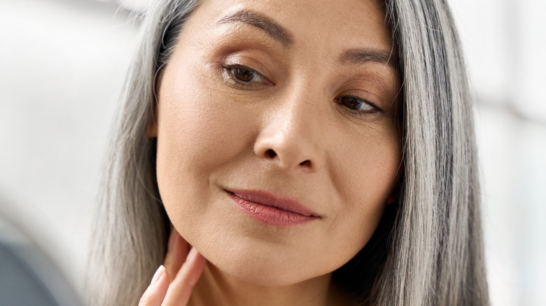 Woman looking at face in mirror