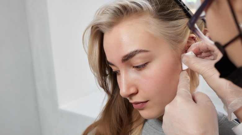 Piercer cleaning woman's tragus