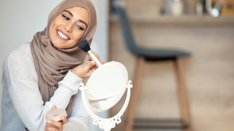 Hijabi woman applying face powder