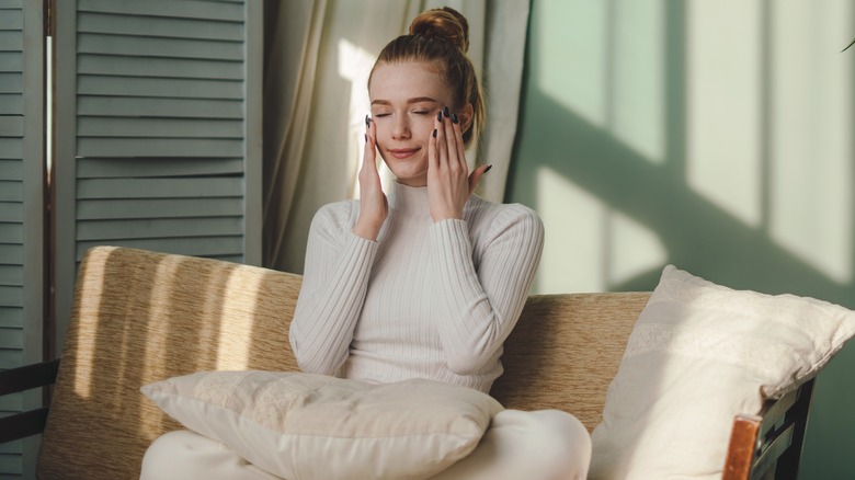 Woman massaging cheek bone tapping