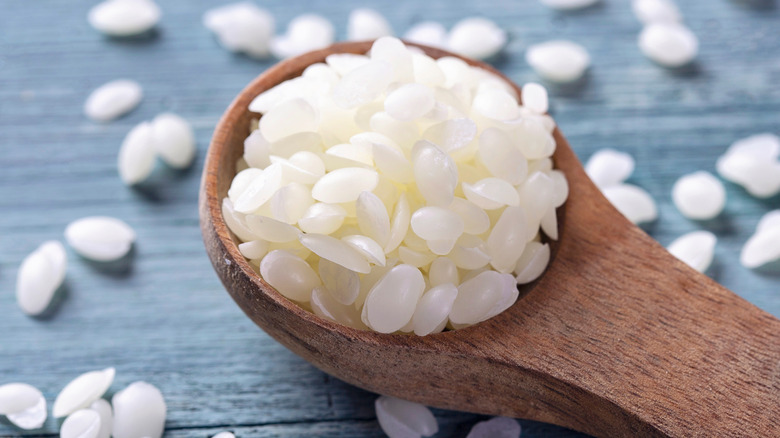 beauty ingredient wax pellets in a wooden spatula 