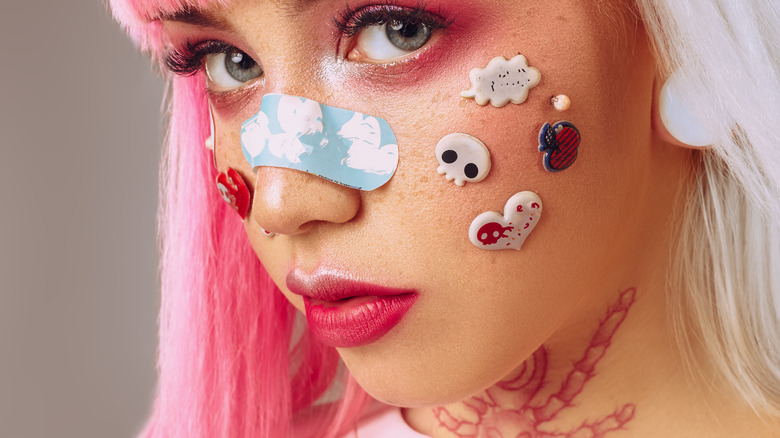 Woman with bright pink kidcore makeup and facial stickers