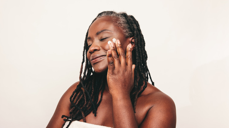 woman applying cream to face