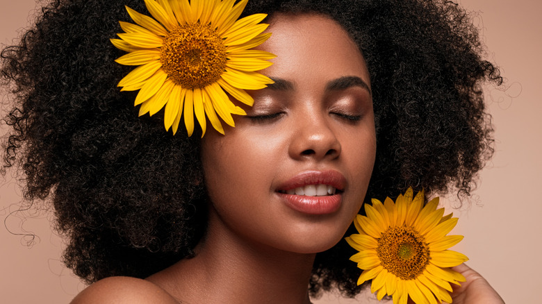 Woman with glowing skin holding sunflowers