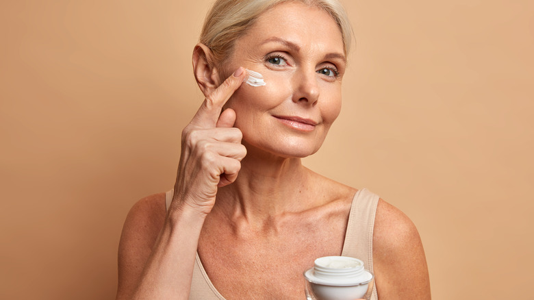 Woman putting cream on face
