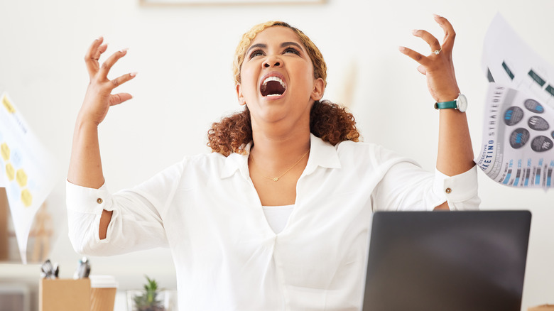Angry working woman screaming with laptop