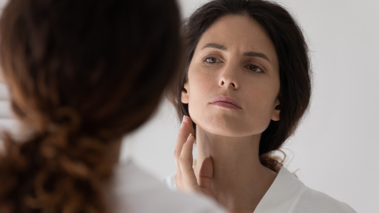 Woman examines jaw in mirror