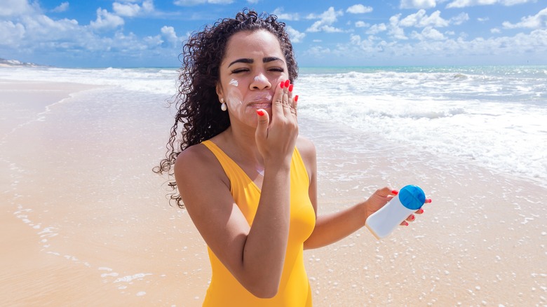woman at beach applying sunscreen