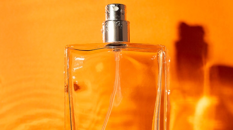 Bottle of perfume against orange background
