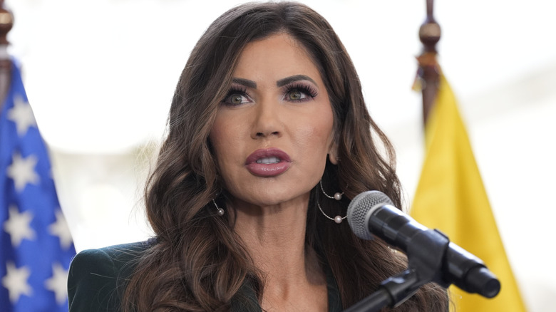 ﻿﻿Kristi Noem, post lip-fillers, photographed while speaking at ﻿a press briefing with Ecuador's Minister while wearing a suit