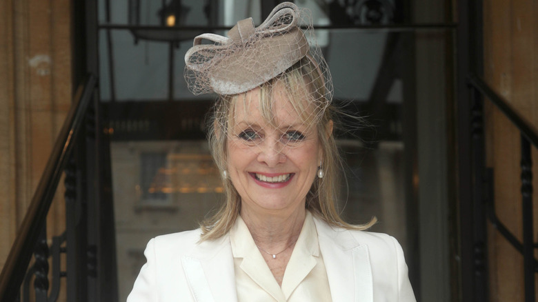 Twiggy wears a white suit and fascinator hat