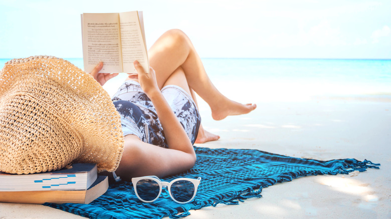 Woman laying on beach reading