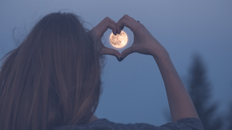 woman framing moon with hands